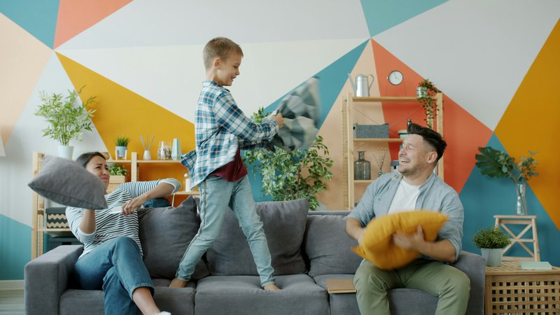 Family having a pillow fight on the couch.